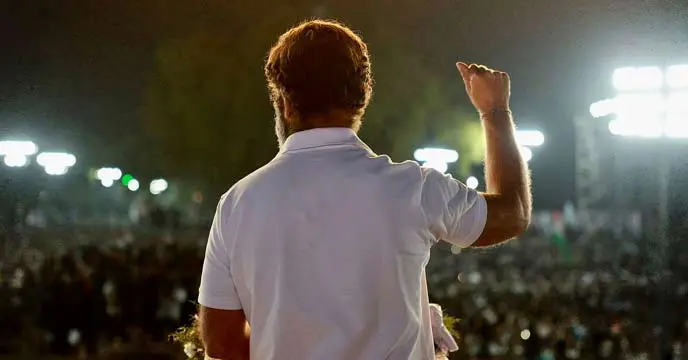 Rahul Gandhi addressing a crowd with "Bharat Jodo" poster in the background