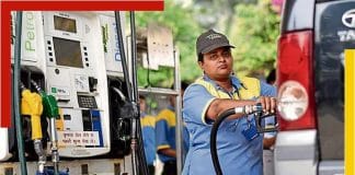 A petrol pump in India with fuel dispensers and vehicles parked in front.