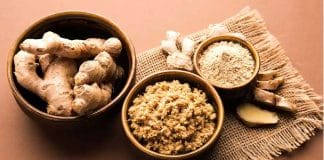Close-up photo of a ginger root with a knife on a wooden board