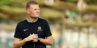 Joseph Gombau standing on a football field wearing a black and yellow tracksuit