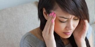 A young woman holding her head in pain, possibly experiencing a migraine