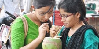 Indian girl drinking coconut water as a solution to contaminated road water