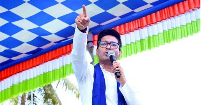 TMC leader Abhishek Banerjee standing in front of a microphone at a political rally