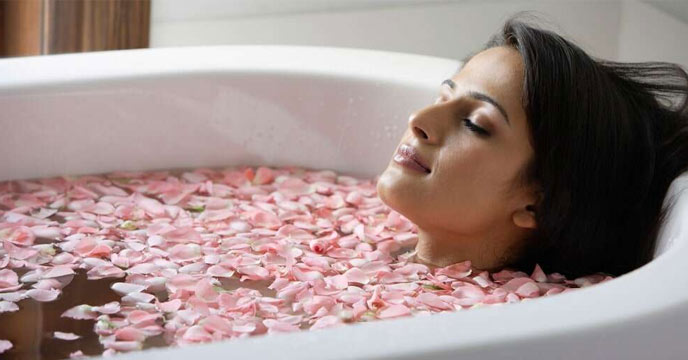 Indian girl pouring rose water into her bath