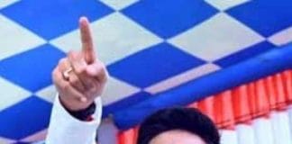 TMC leader Abhishek Banerjee standing in front of a microphone at a political rally