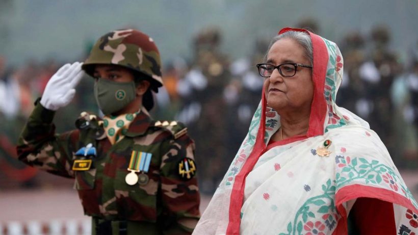 Bangladesh Prime Minister Sheikh Hasina giving a serious address or warning. She is dressed in traditional attire, and the image captures her with a focused expression, likely speaking at an official event or press conference.