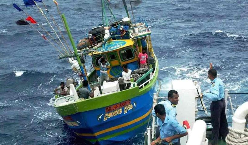Image of Sri Lankan Navy personnel detaining Tamil Nadu fishermen, with two seized fishing boats in the background, following a reported apprehension incident.