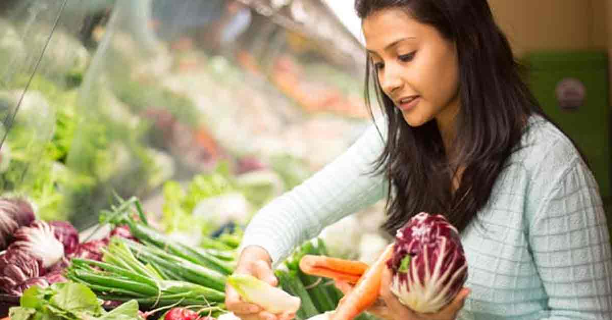 A variety of fresh vegetables arranged neatly on a surface. The assortment includes carrots, bell peppers, cucumbers, and tomatoes, showcasing vibrant colors and different shapes.