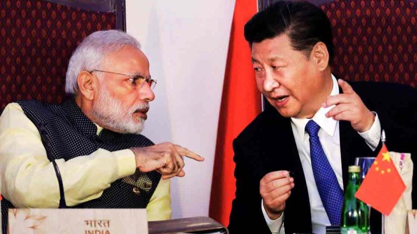 Prime Minister Narendra Modi and President Xi Jinping of China are seen together in this photo. They are both dressed in formal attire, with Modi wearing a traditional Indian suit and Jinping in a dark suit with a tie. They appear to be engaged in a cordial conversation or meeting, with a backdrop of a neutral, professional setting.