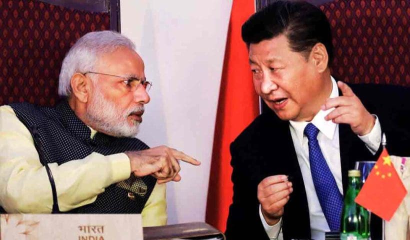 Prime Minister Narendra Modi and President Xi Jinping of China are seen together in this photo. They are both dressed in formal attire, with Modi wearing a traditional Indian suit and Jinping in a dark suit with a tie. They appear to be engaged in a cordial conversation or meeting, with a backdrop of a neutral, professional setting.