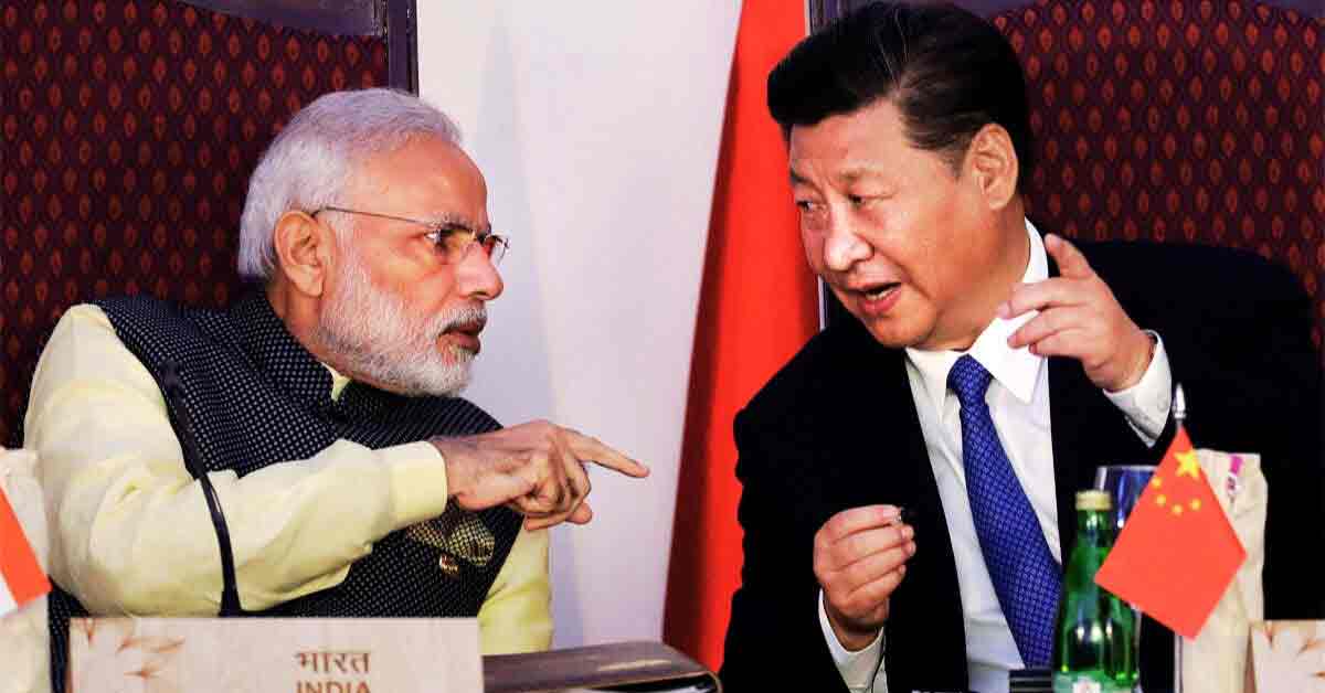 Prime Minister Narendra Modi and President Xi Jinping of China are seen together in this photo. They are both dressed in formal attire, with Modi wearing a traditional Indian suit and Jinping in a dark suit with a tie. They appear to be engaged in a cordial conversation or meeting, with a backdrop of a neutral, professional setting.